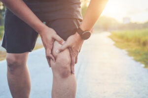 man holding knee in pain while jogging