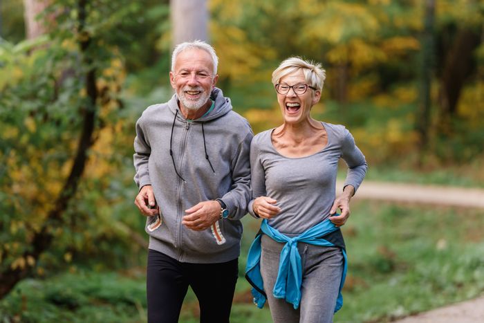 Cheerful active senior couple jogging in the park. Exercise together to stop aging